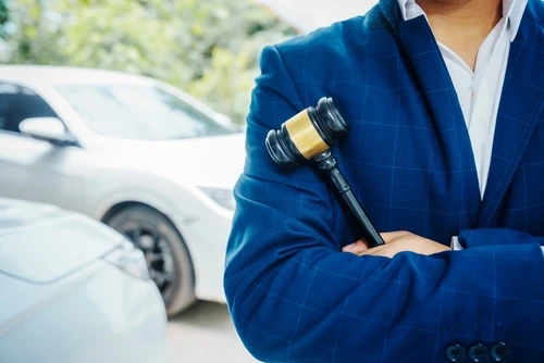 A Georgia car accident lawyer stands beside a vehicle with a gavel.