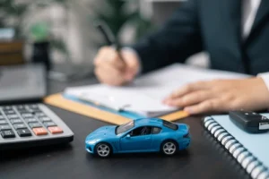 Man Signing Document with Calculator and Toy Car