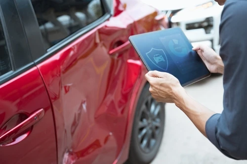 A man files a car insurance claim using a tablet after an accident.
