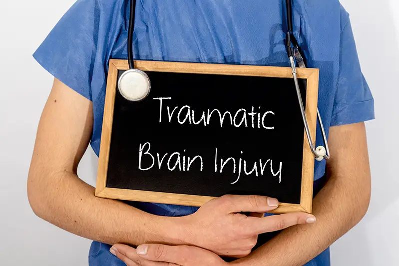 Nurse holding sign that says Traumatic Brain Injury