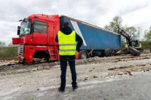A safety official is inspecting the damaged red semi-truck accident scene, representing a Georgia truck accident investigation and liability assessment.