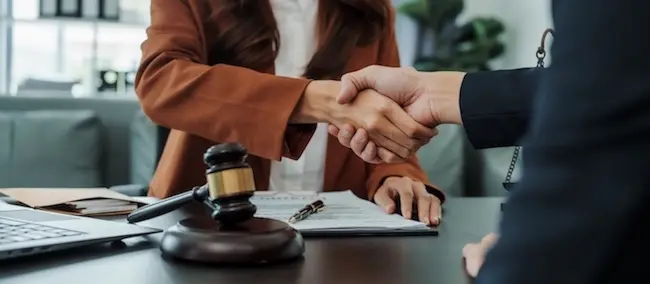 An attorney and a client are shaking hands after discussing a commercial vehicle liability case and legal representation options.
