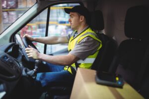 A professional delivery driver is in a safety vest and is operating a delivery van which is highlighting the risks of Amazon delivery car accidents on the urban routes in Georgia.