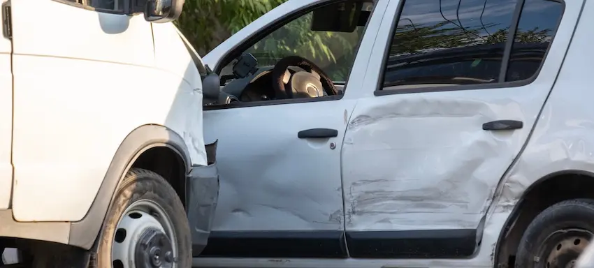 A white delivery van with significant side door damage and dented panels from delivery driver accidents collision in Georgia.