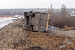 An overturned commercial truck on a roadside embankment shows dangerous conditions that create truck accident victims in Georgia.