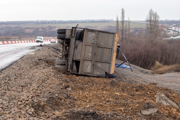 An overturned commercial truck on a roadside embankment shows dangerous conditions that create truck accident victims in Georgia.