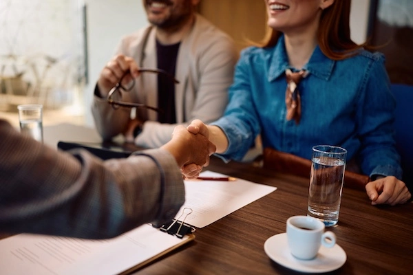 A truck accident lawyer is shaking hands with a female client at 1Georgia Personal Injury Lawyers.